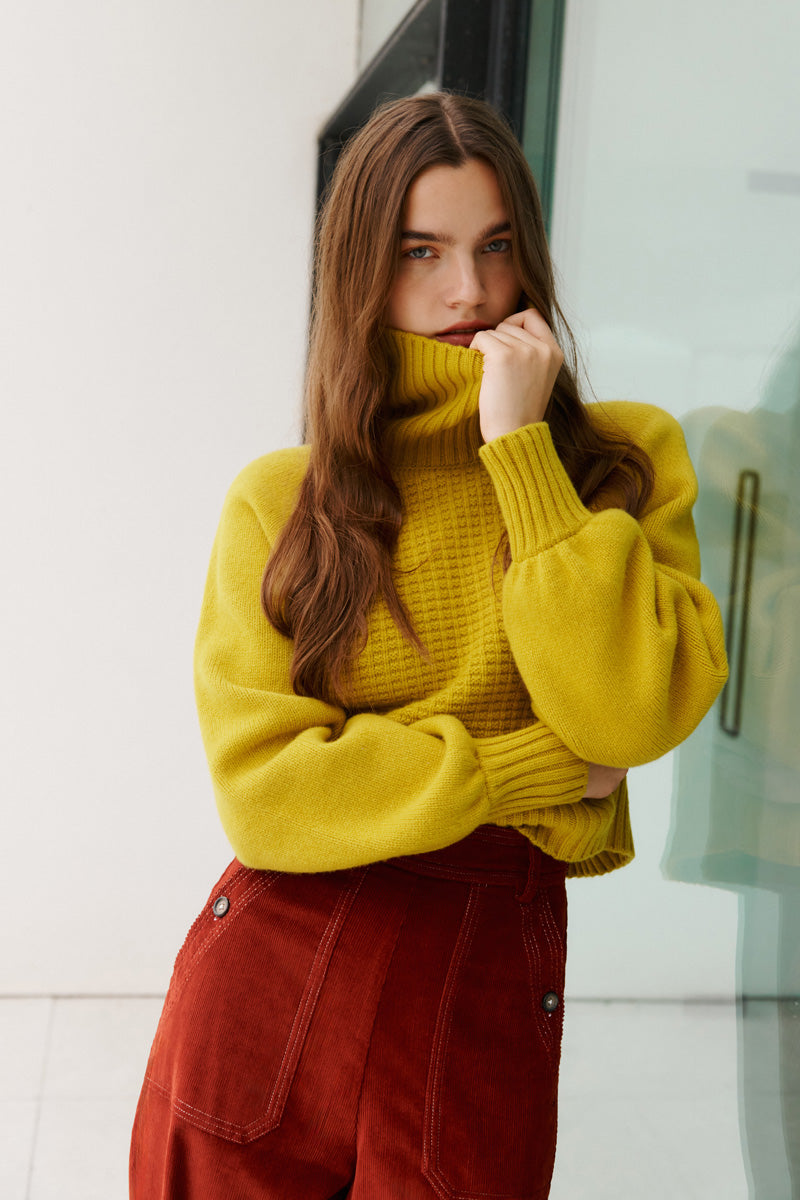 Wiggy Kit | Waffle Turtleneck in Yellow | Model Wearing Yellow Jumper and Red Jeans