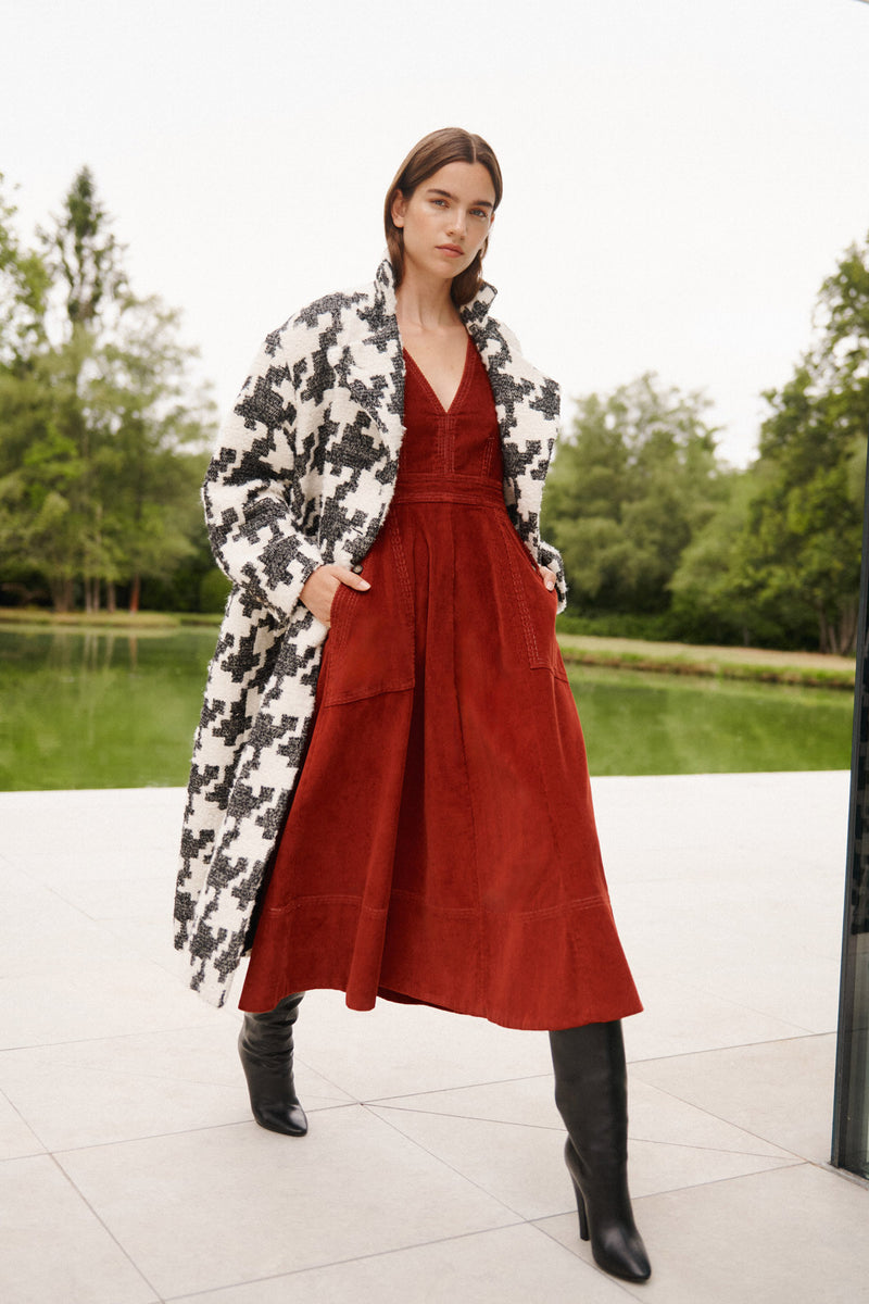 Wiggy Kit | Lantern Dress | Model Wearing Red Lantern Dress with Black Boots and Aztec Print White and Black Coat