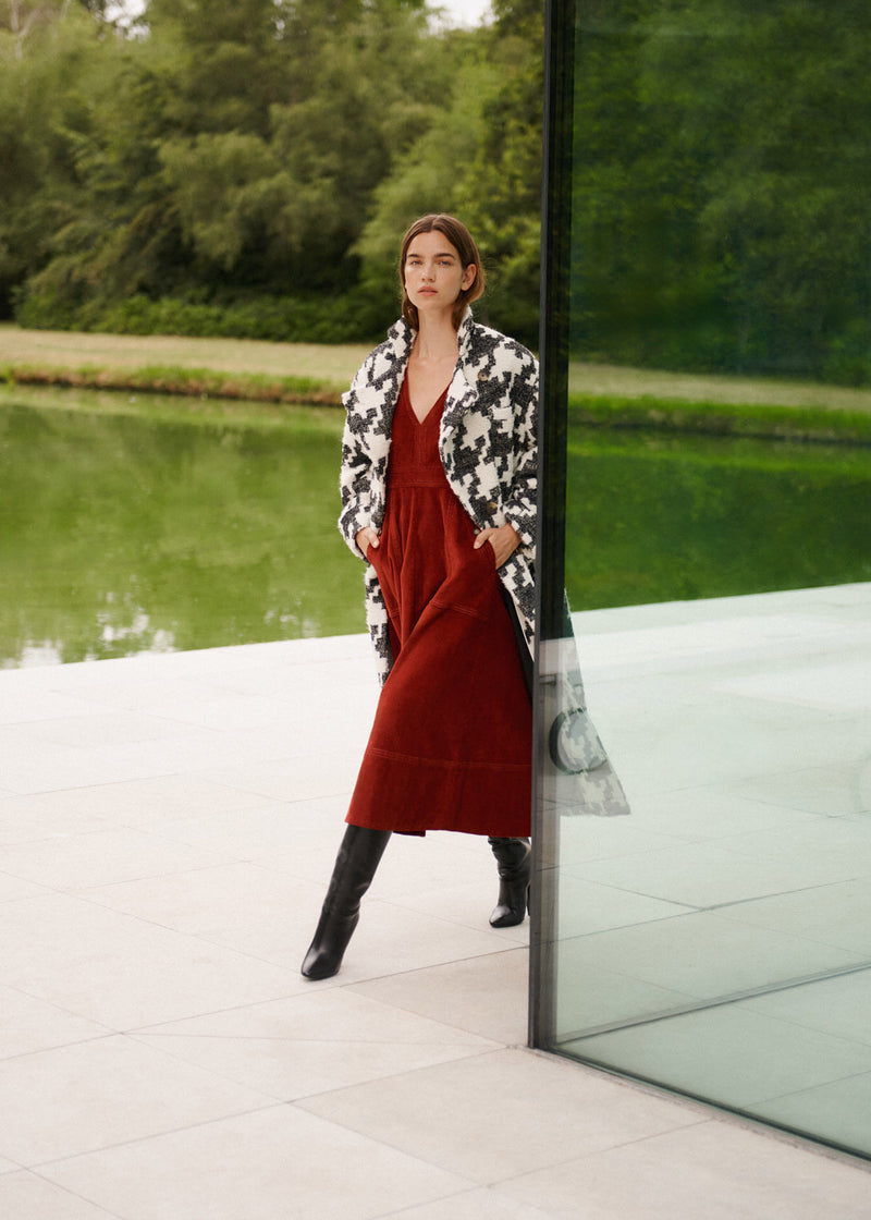 Wiggy Kit | Lantern Dress | Model Wearing Red Lantern Dress with Black Boots and Aztec Print White and Black Coat