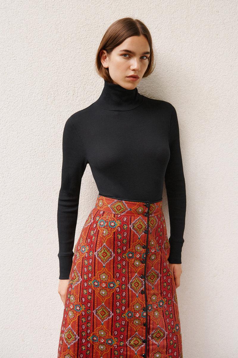 Wiggy Kit | The Quilted Skirt in Orange Multi Print | Model Wearing Black Top with Orange Print Skirt