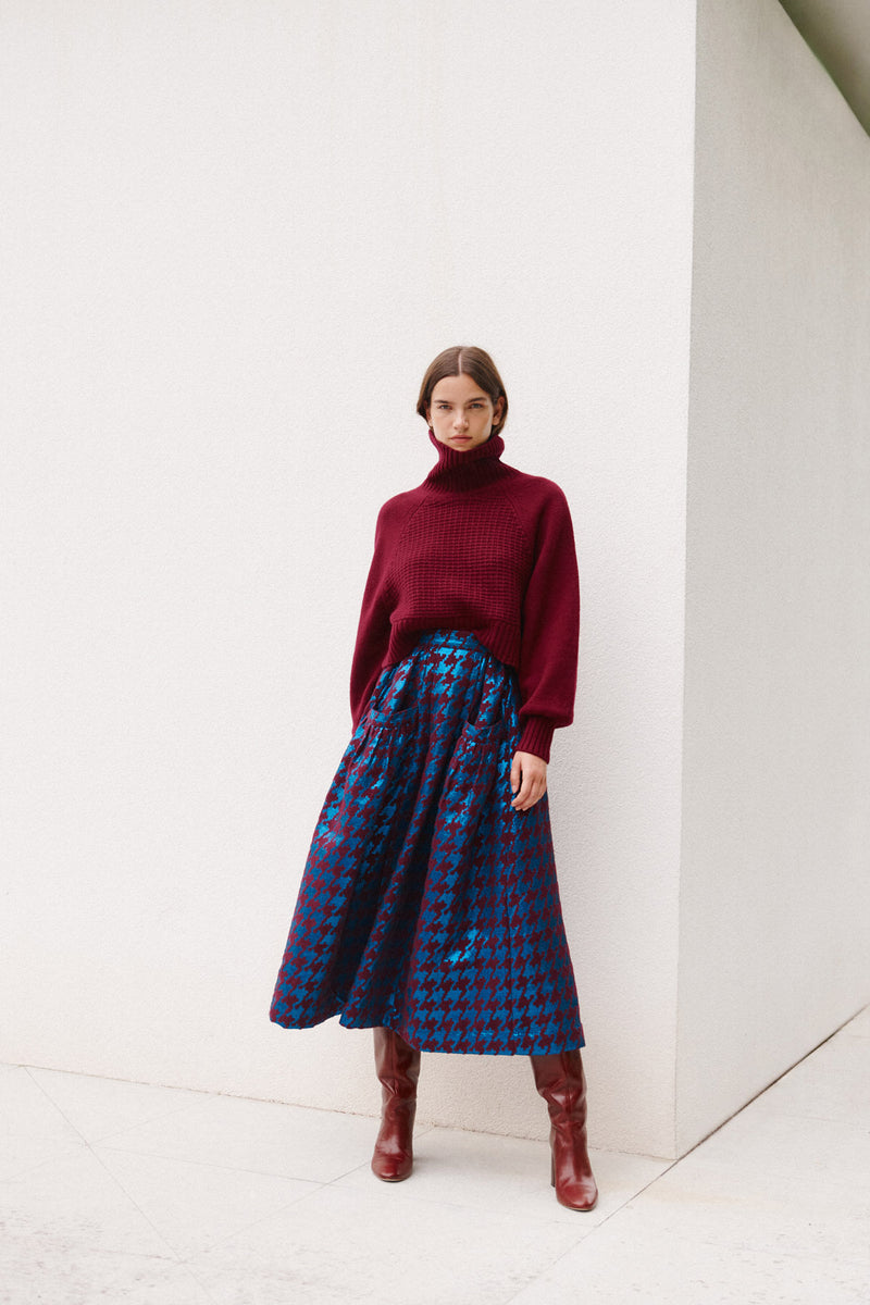 Wiggy Kit | Waffle Turtleneck in Dark Red | Model Wearing Dark Red Jumper and Patterned Skirt