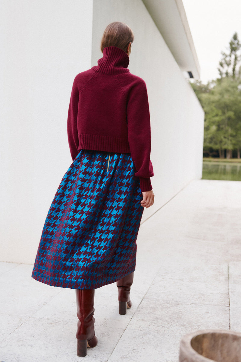 Wiggy Kit | Waffle Turtleneck in Dark Red | Model Wearing Dark Red Jumper and Patterned Skirt