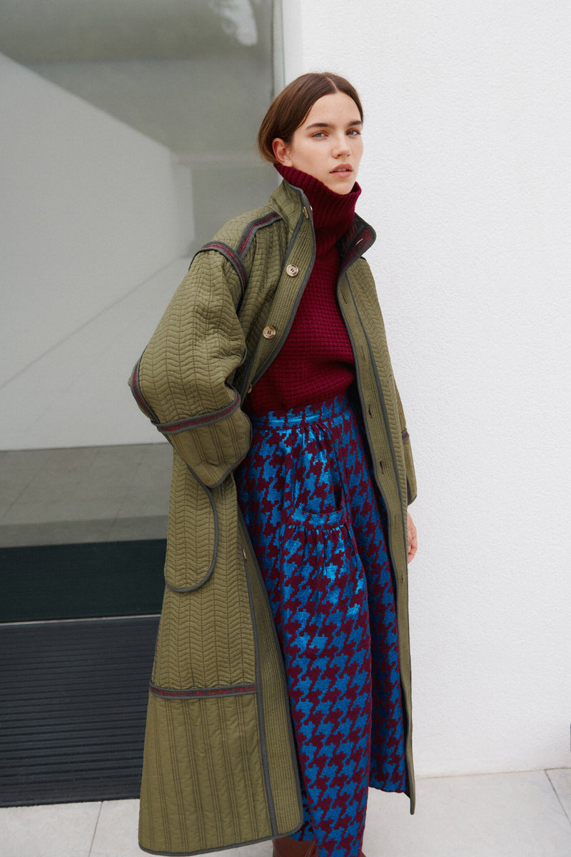 Wiggy Kit | Houndstooth Gaucho Skirt | Model Wearing Houndstooth Gaucho Skirt with Red Knitted Jumper and Long Green Coat