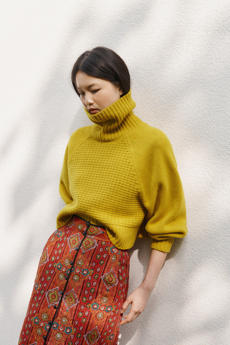 Wiggy Kit | Waffle Turtleneck in Yellow | Model Wearing Yellow Jumper and Red Skirt
