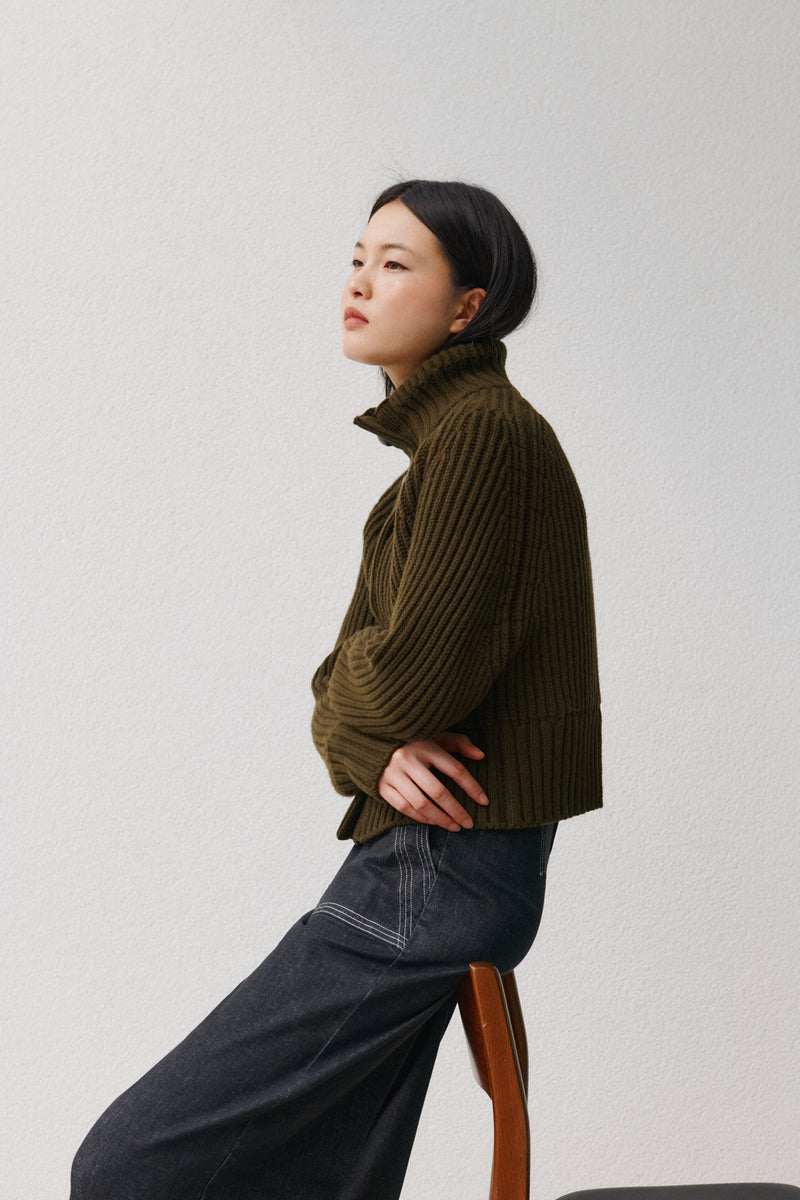 Wiggy Kit | Ribbed High Neck Jacket in Green | Model Wearing Ribbed High Neck Jacket with Jeans