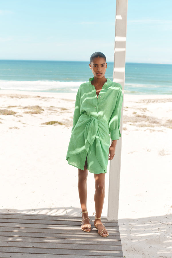 Wiggy Kit | Mini Sarong Shirt Dress | Model wearing green shirt dress with beach background