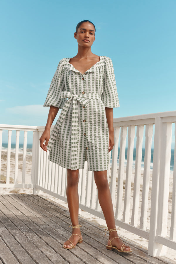 Wiggy Kit | Mini Square Neck Dress | Model wearing green and cream gingham print with beach in background