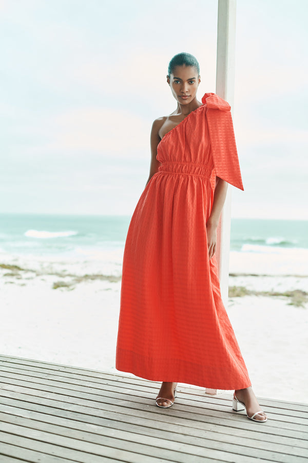 Wiggy Kit | The Minnie Maxi | Model wearing one shoulder orange maxi dress with oversized bow