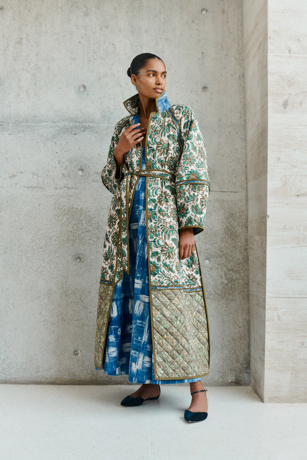Wiggy Kit | Quilted Raglan Coat | Model wearing long floral reversible coat with blue dress underneath