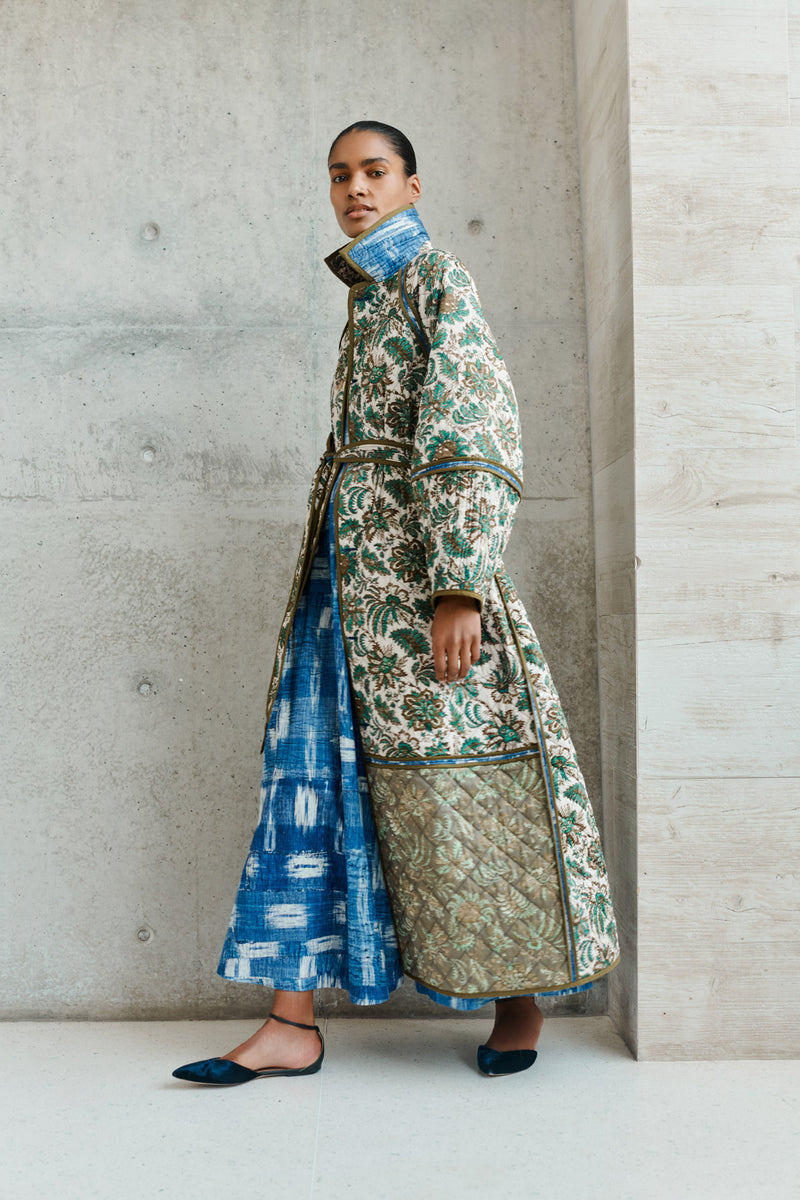 Wiggy Kit | Quilted Raglan Coat | Model wearing long floral reversible coat with blue dress underneath