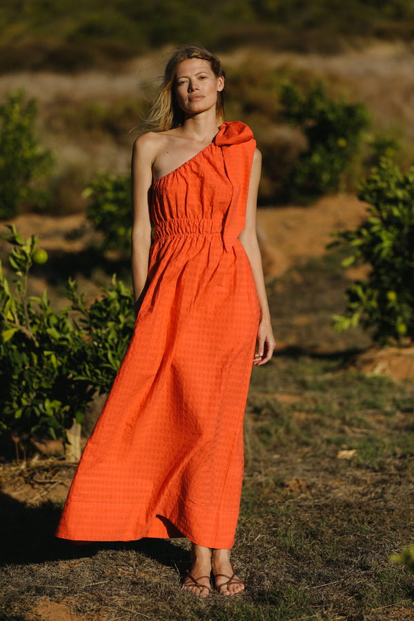 Wiggy Kit | The Minnie Maxi | Model wearing one shoulder orange maxi dress with oversized bow